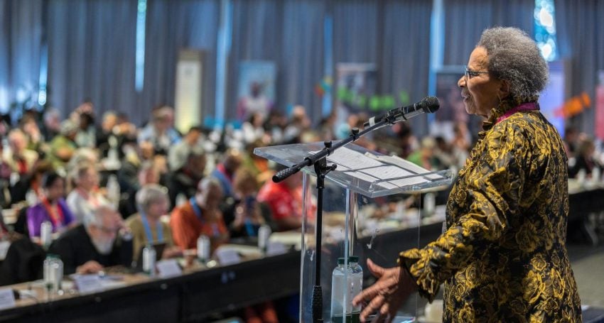 A woman addresses an audience from a stage at an international conference