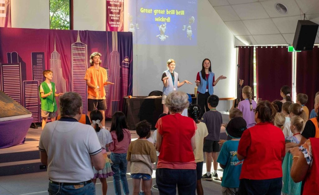 Kids at a church kids club with people in the sanctuary area leading a dance