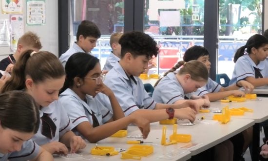 A group of students are seated at a table working on a solar kit