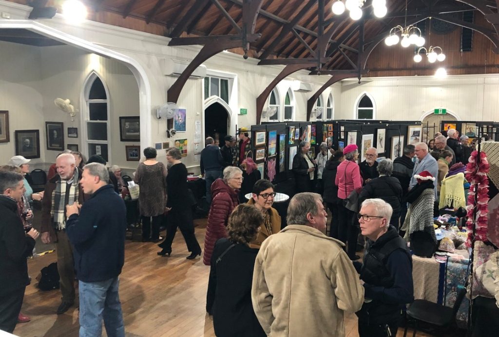 Church hall filled with people at an art exhibition opening night