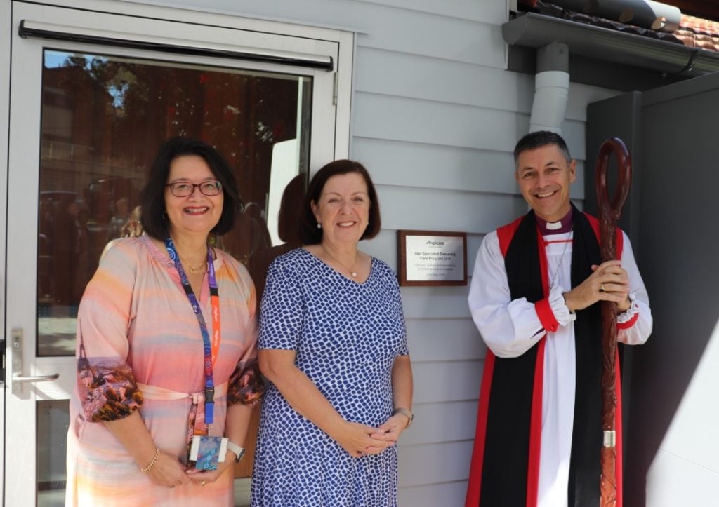 An Archbishop and two women in front of a plaque on a new building