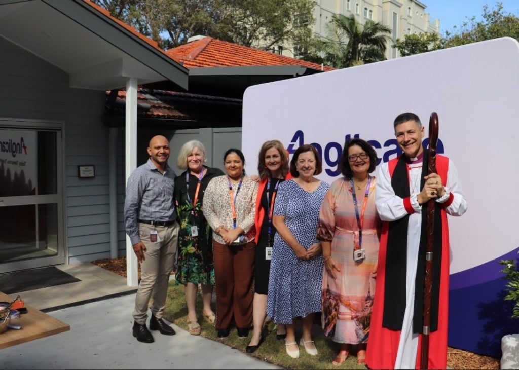 Group of people with an Archbishop outside in front of an Anglicare sign