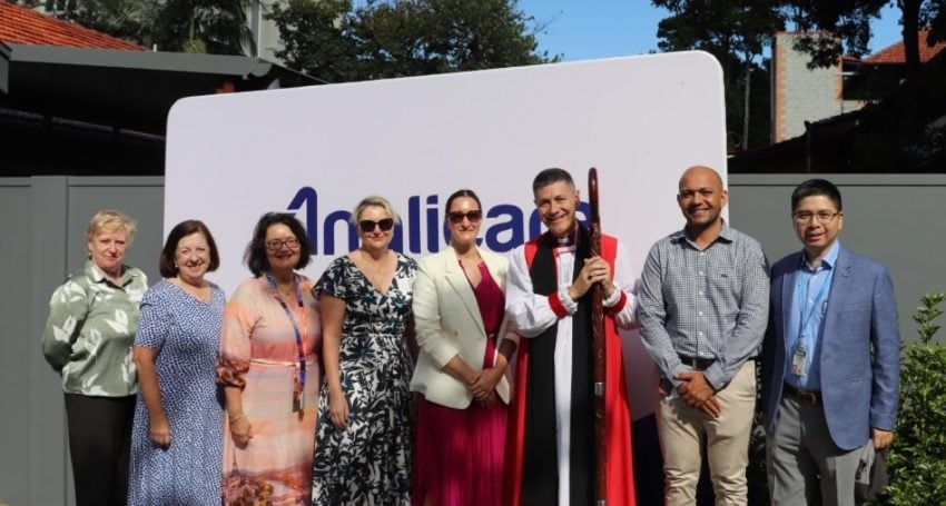 Group of people with an Archbishop outside in front of an Anglicare sign