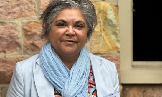 Woman in blue scarf and jacket looking at the camera with a soft smile