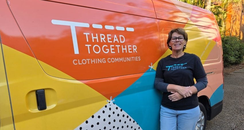 A woman stands in front of a Thread Together van