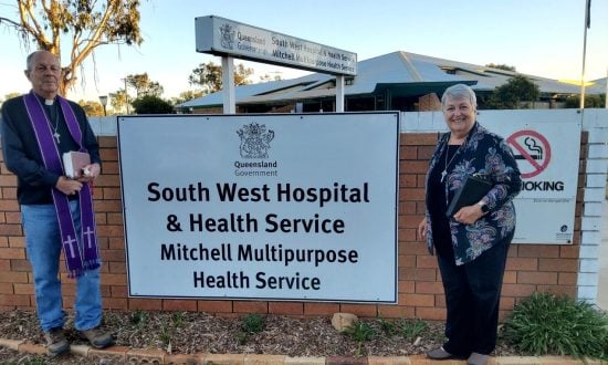 A priest and a woman outside a rural hospital