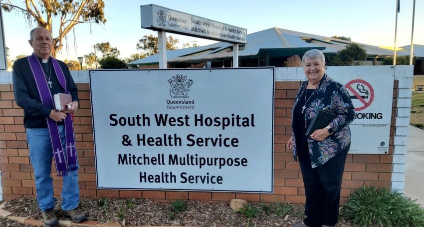 A priest and a woman outside a rural hospital