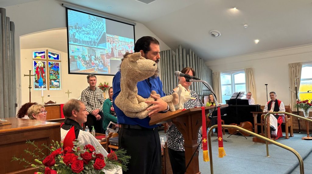Two puppeteers at a lectern during a church service 