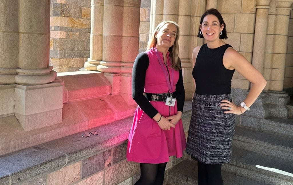 Two women outside a cathedral smiling at a camera