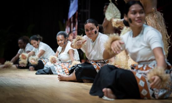 A group of women perform on stage in traditional cultural outfits