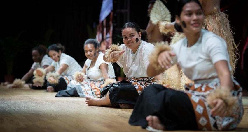 A group of women perform on stage in traditional cultural outfits
