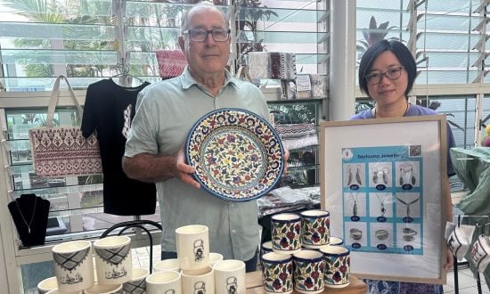 A man and a woman selling ceramics and jewellery at a stall