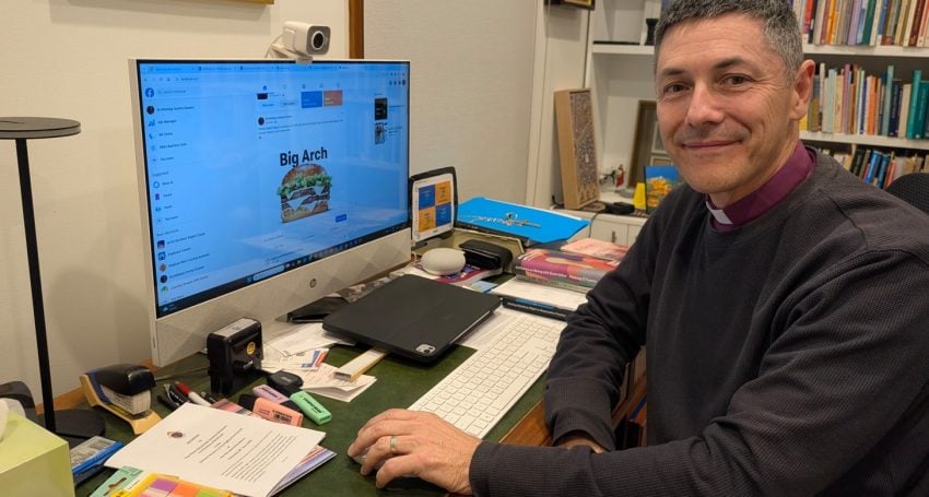 Archbishop in front of computer smiling