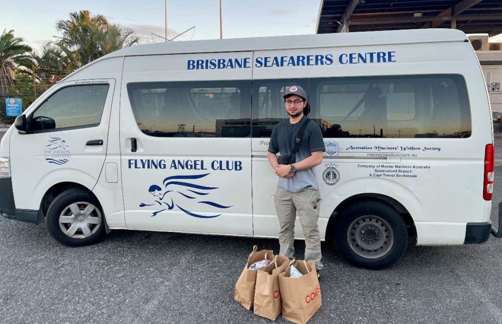 Seafarer standing in front of a white bus with shopping bags