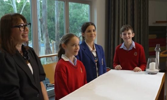 Students and staff from Cannon Hill Anglican College stand around a table listening to a conversation