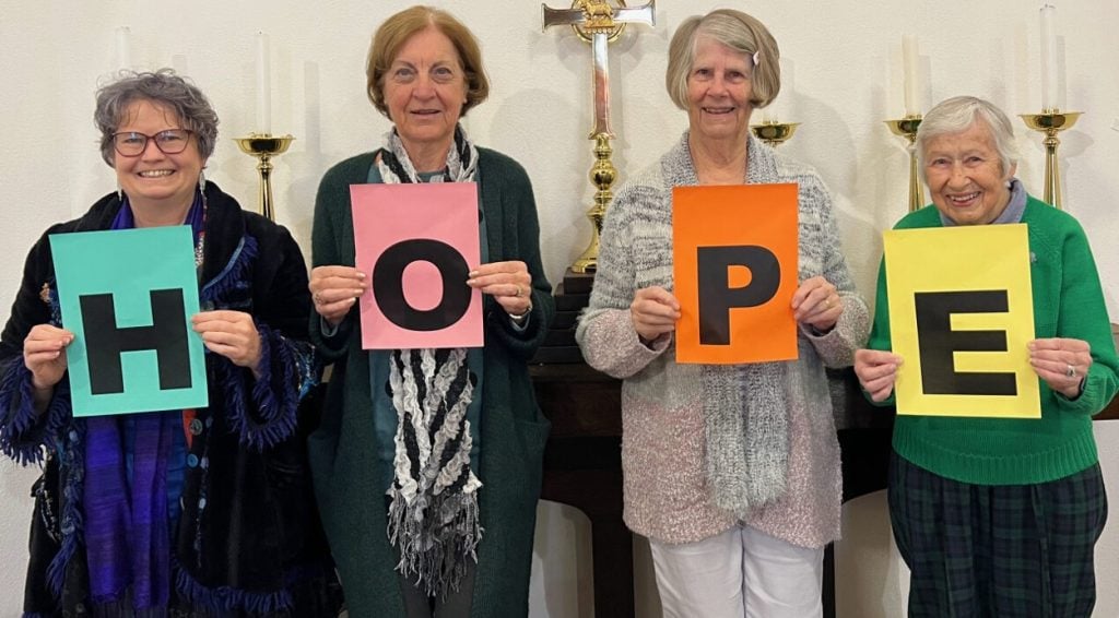 Four women holding up a coloured "Hope" sign 
