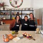 Three women stand in the My Dilly Bag kitchen posing for a photograph