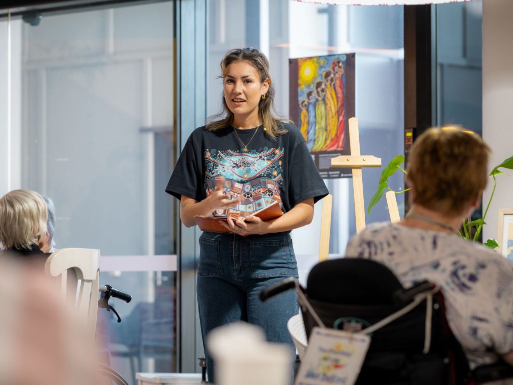 A woman stands in front of an audience ready to teach a class