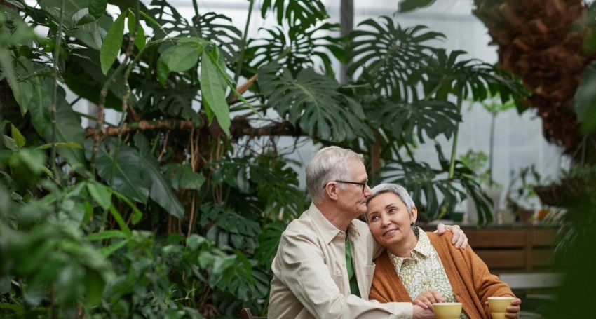A couple embrace while sitting in front of a garden