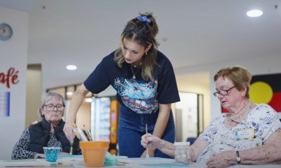 A woman demonstrates art practice during a lesson to aged care residents
