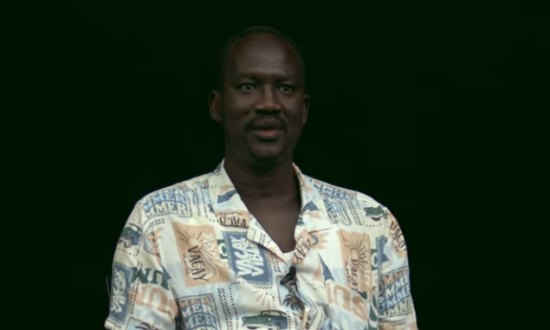A man looks at the camera for an interview against a black background