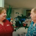 A man and woman engage in conversation in a living room