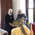 Two women pose for a photograph with vestments available