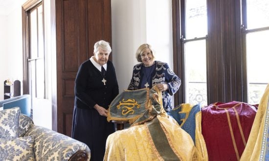 Two women pose for a photograph with vestments available